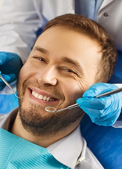 Man in dental chair smiling about to have teeth examined