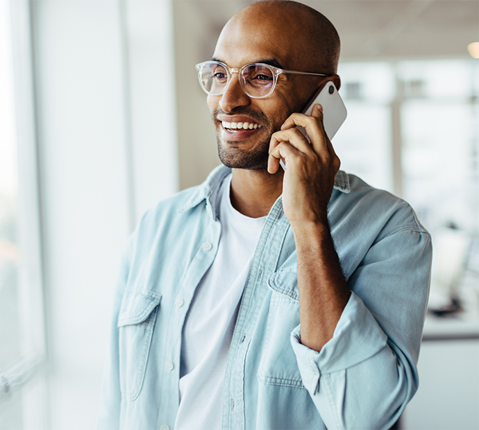 Man with glasses and denim jacket talking on phone