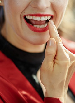 Woman pointing to dental crown in Dix Hills