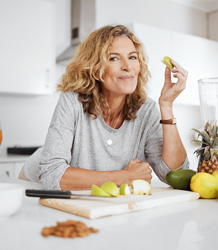 Woman in grey shirt eating an apple slice