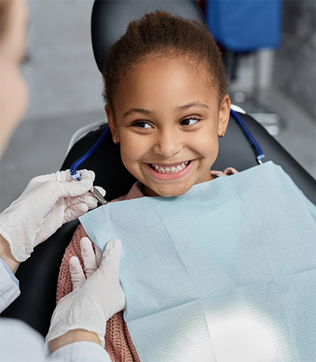 Little girl in dental chair smiling at dentist