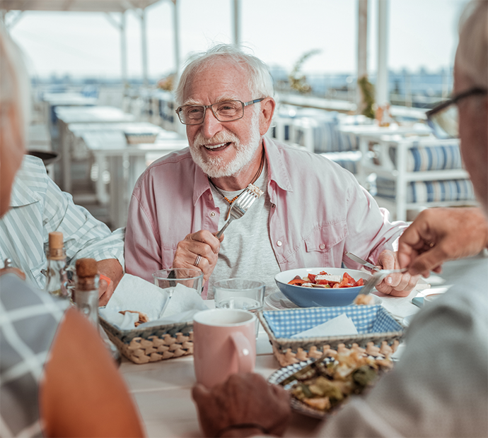 Older man with glasses enjoying meal with others at restaurant