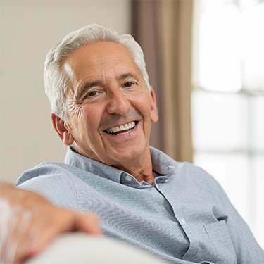 Smiling man in button-up shirt sitting on a couch
