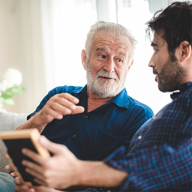 Bearded man in blue shirt talking to another man