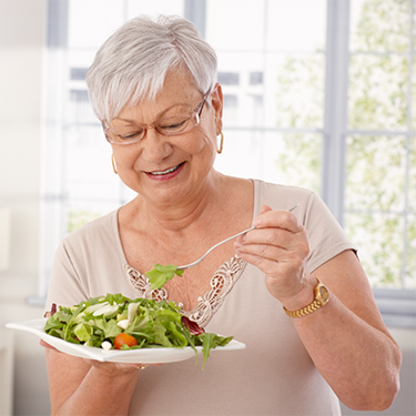 Older woman with glasses eating a salad