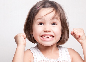 A little girl smiling with a few missing teeth