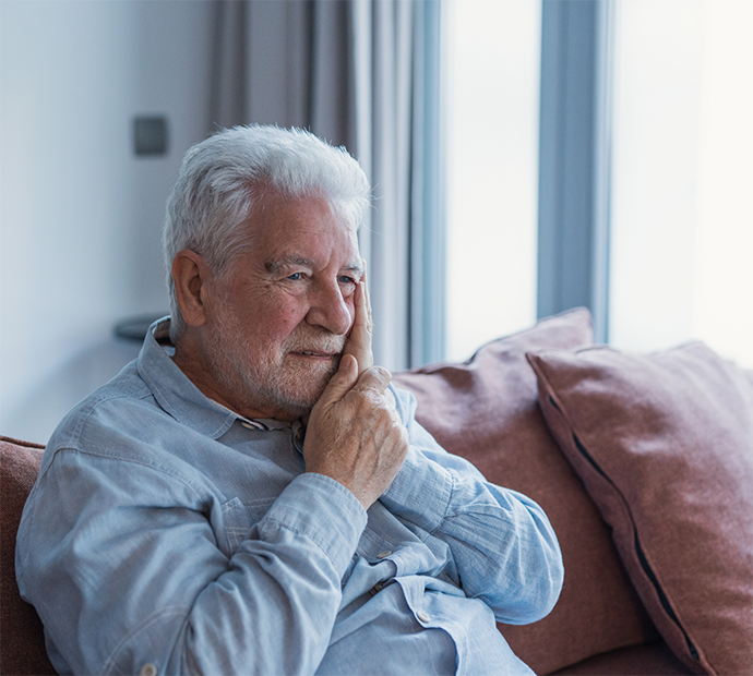 Man with oral pain sitting on couch and rubbing his jaw
