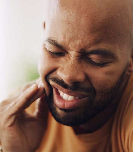 Close-up of bearded man in pain due to failed dental implant