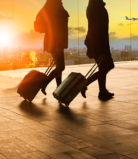 Two people walking through an airport and pulling their suitcases behind them