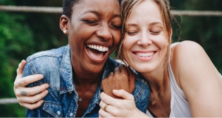Two women hugging from the side outdoors