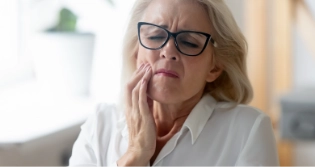 Older woman with glasses experiencing dental pain