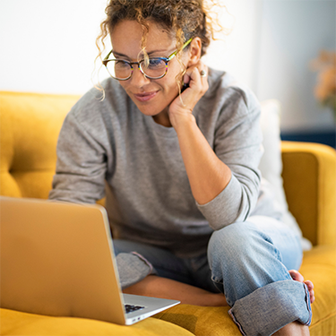 Woman in grey shirt typing on a laptop