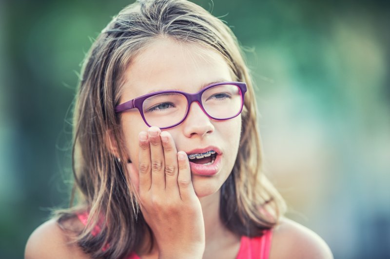 little girl holding her jaw in pain