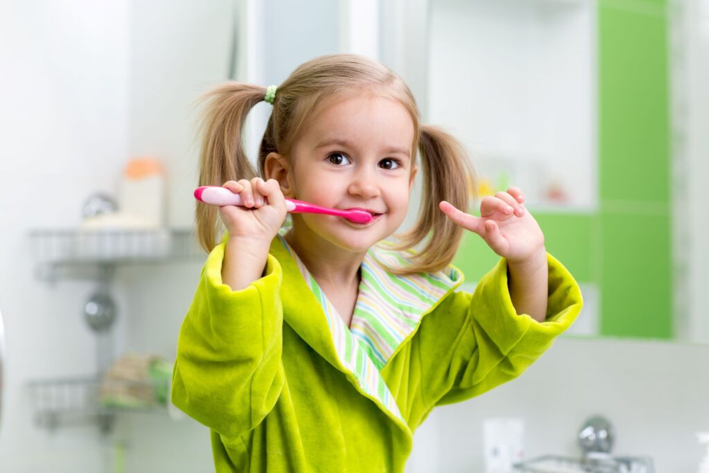 Girl in green robe in bathroom brushing teeth